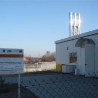 tablica informacyjna oraz biały budynek znajdujący się z prawej strony